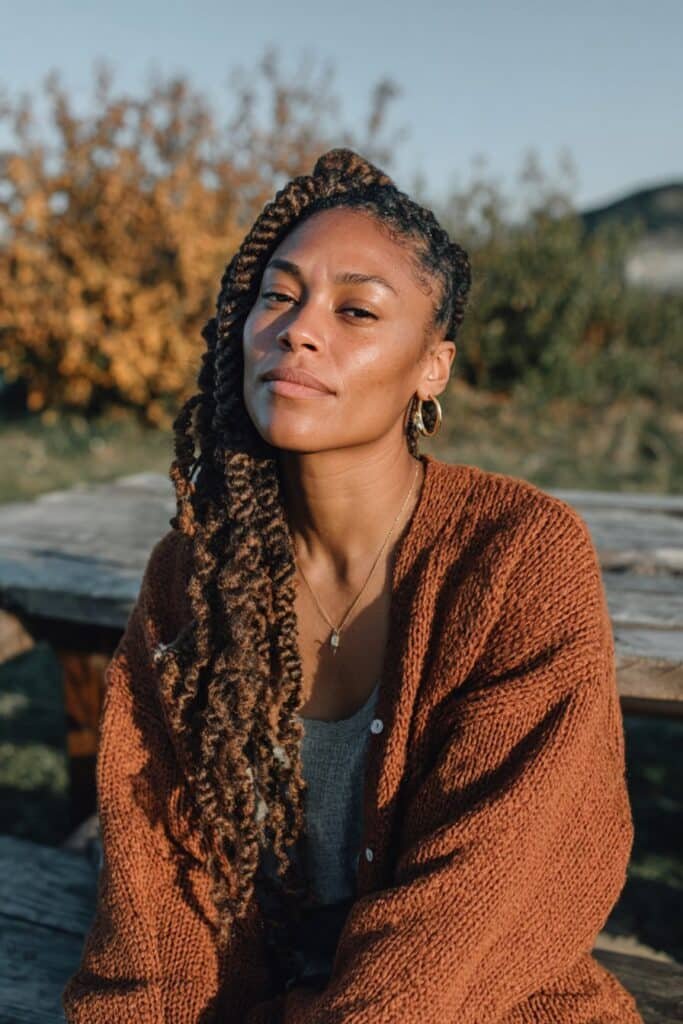 Black woman wearing long chunky box braids swept over one shoulder.