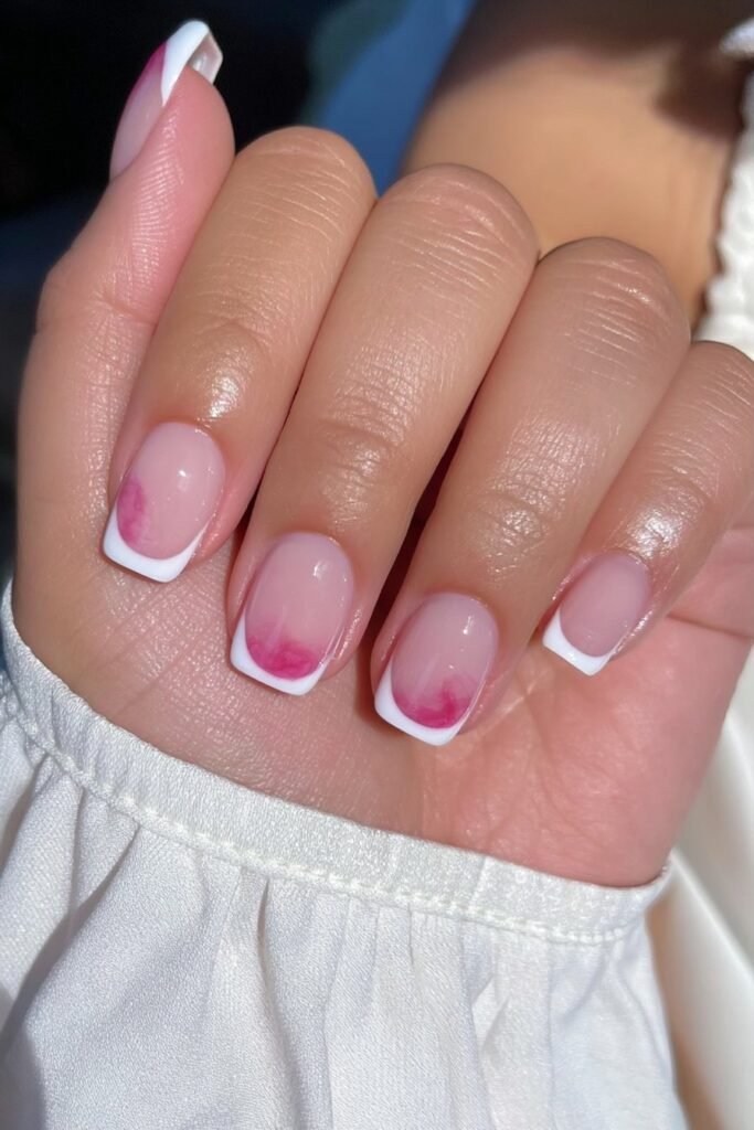 Short French tip nails with a sheer blush pink base.