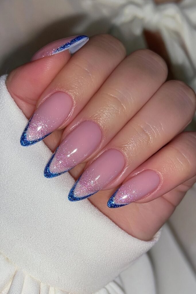 Sheer nude almond nails with crisp cobalt blue French tips.