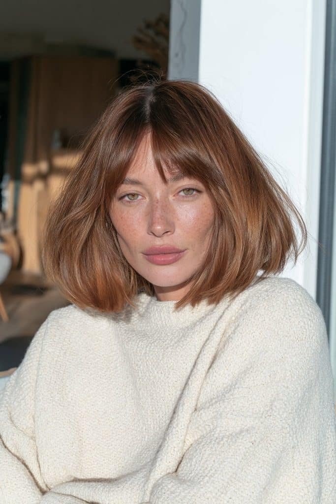 Young woman with a dimensional copper jellyfish haircut in auburn and cinnamon tones.