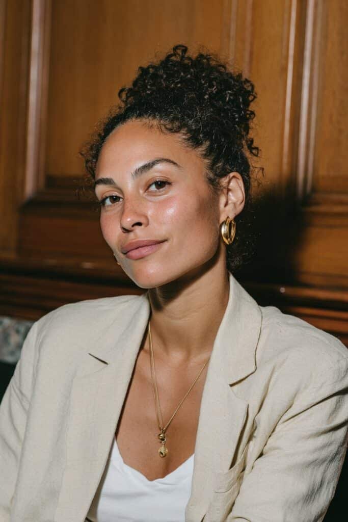 Young woman with a curly bun and soft face-framing tendrils