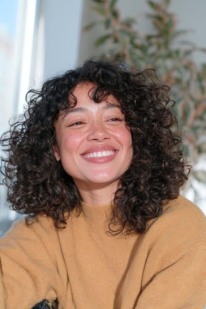 Young Black woman with a curly jellyfish haircut featuring defined natural dark curls.