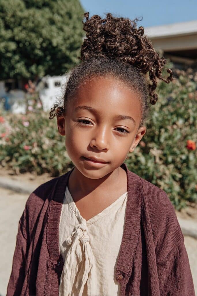 Little Black girl with a high natural-textured drawstring bun.
