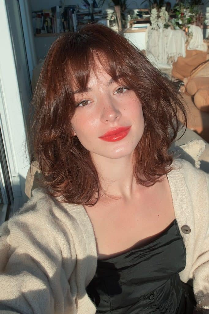 Young woman with an effortlessly tousled chocolate-brown jellyfish haircut and relaxed waves.