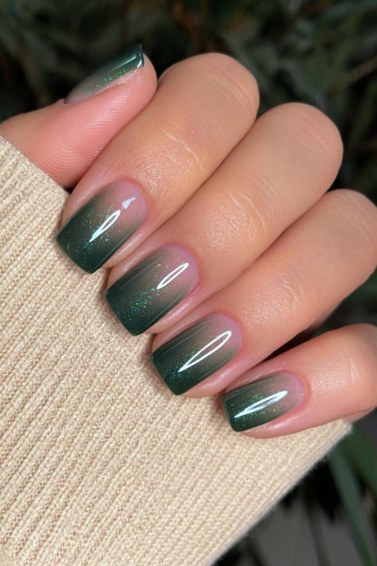Short nude nails with a forest green accent nail.