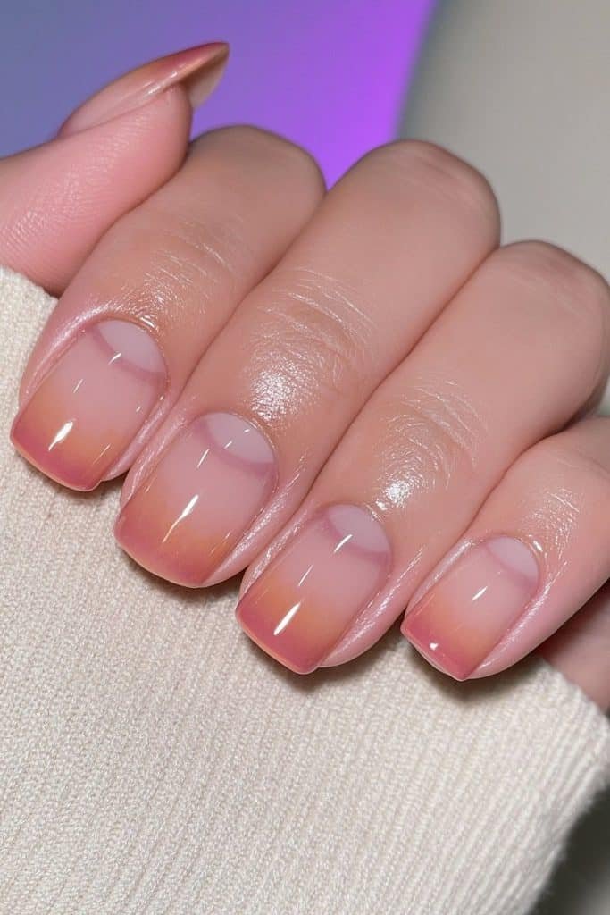 Short nude nails with French orange tips.