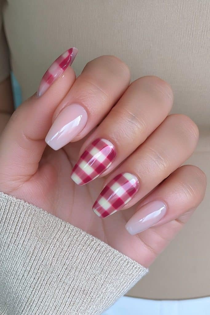 Short squoval Thanksgiving nails with creamy nude bases and cranberry gingham accents.