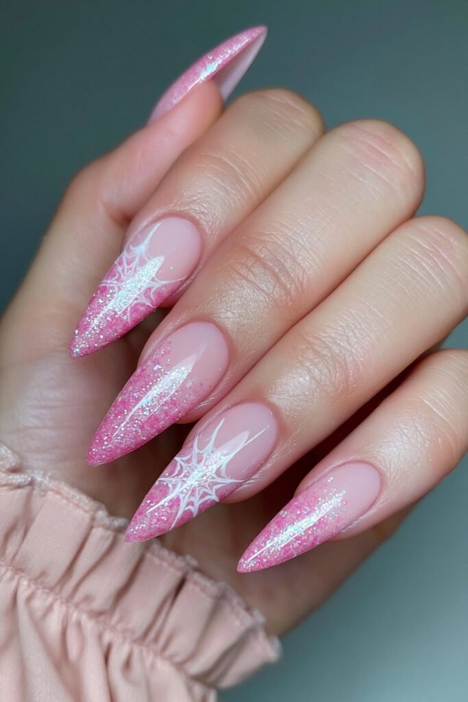 Glittery pink nails with white spider web accents.