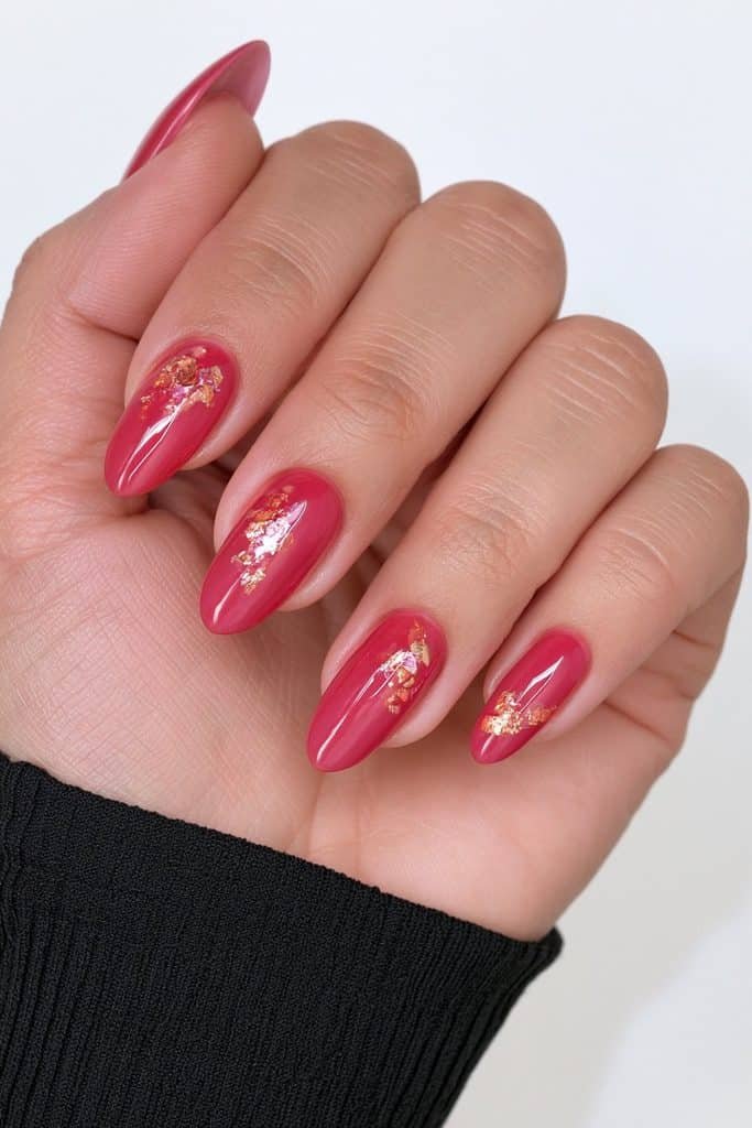 Short glossy red almond nails with delicate metallic gold foil accents.
