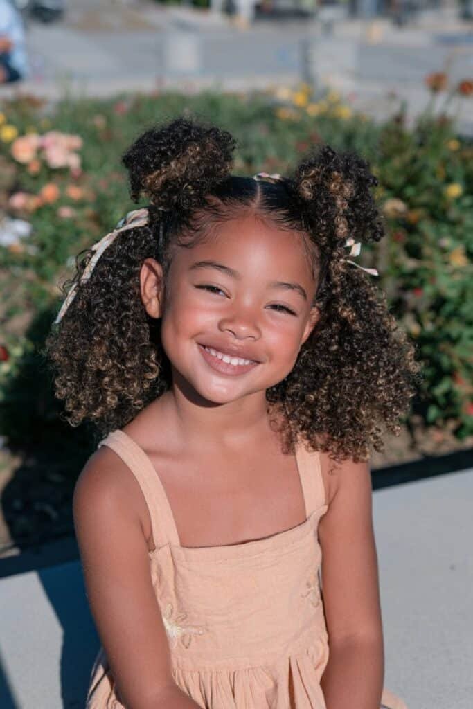 Little Black girl with half-up half-down puffs and peach ribbons