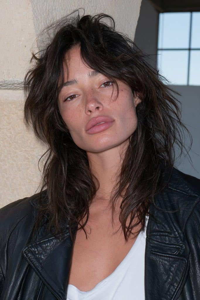 Young woman with a textured jellyfish wolf cut featuring choppy layers and long feathered lengths.