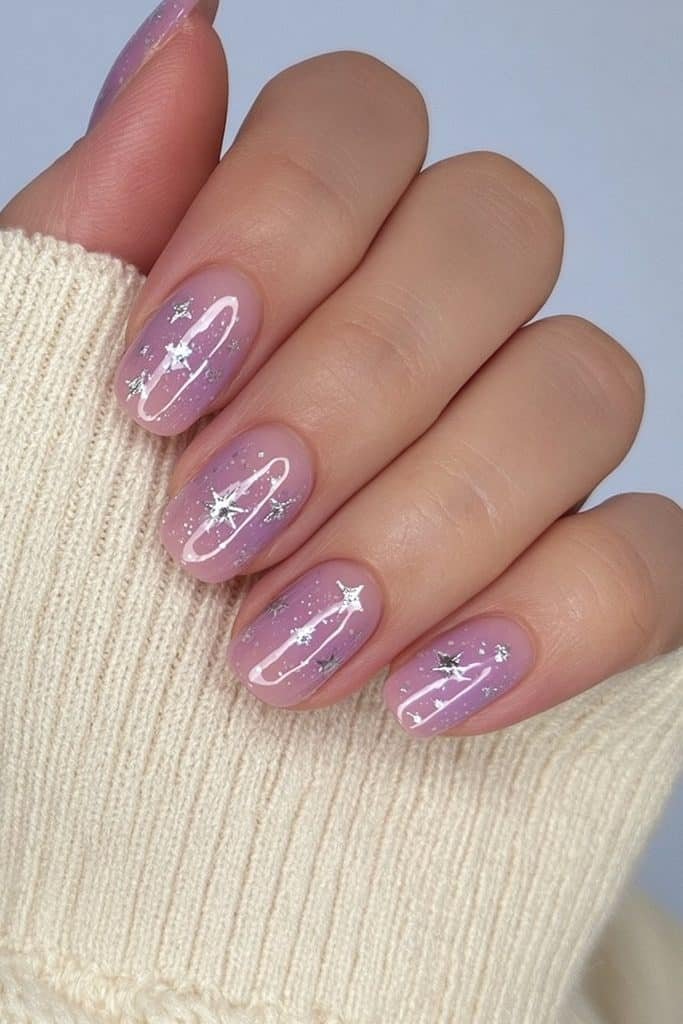 Short soft lilac nails decorated with tiny silver stars and celestial details.