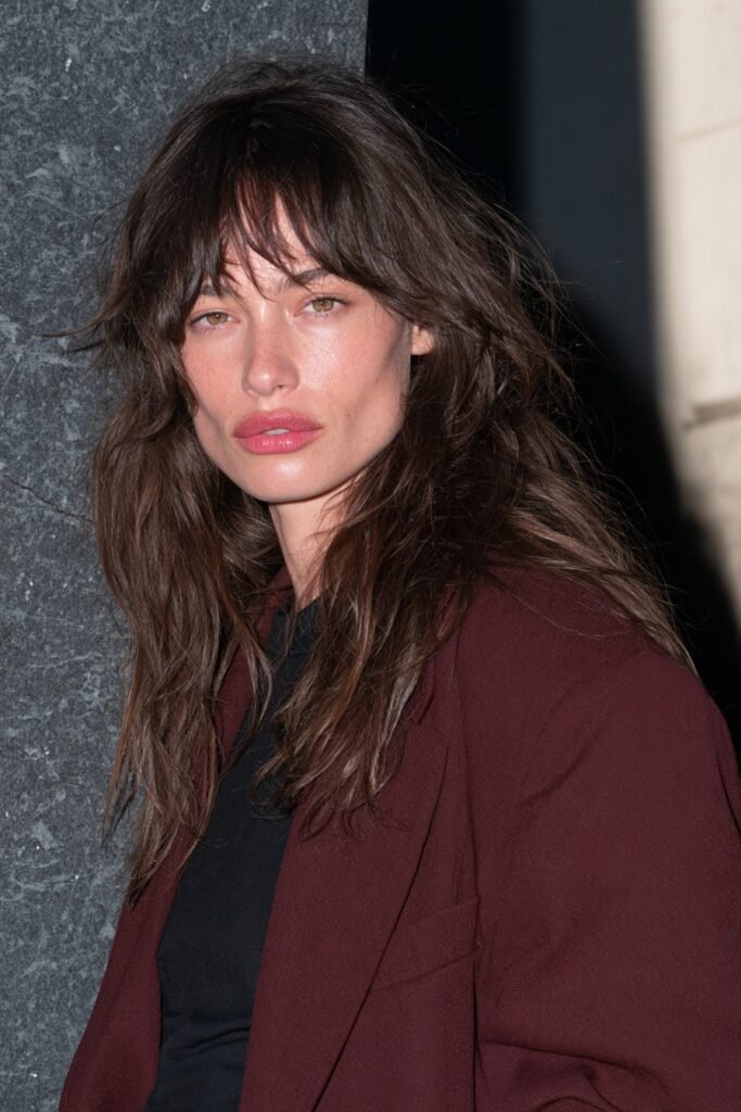 Long deep brunette wolf haircut with a heavily textured crown, choppy layers, and bold blunt uneven ends.