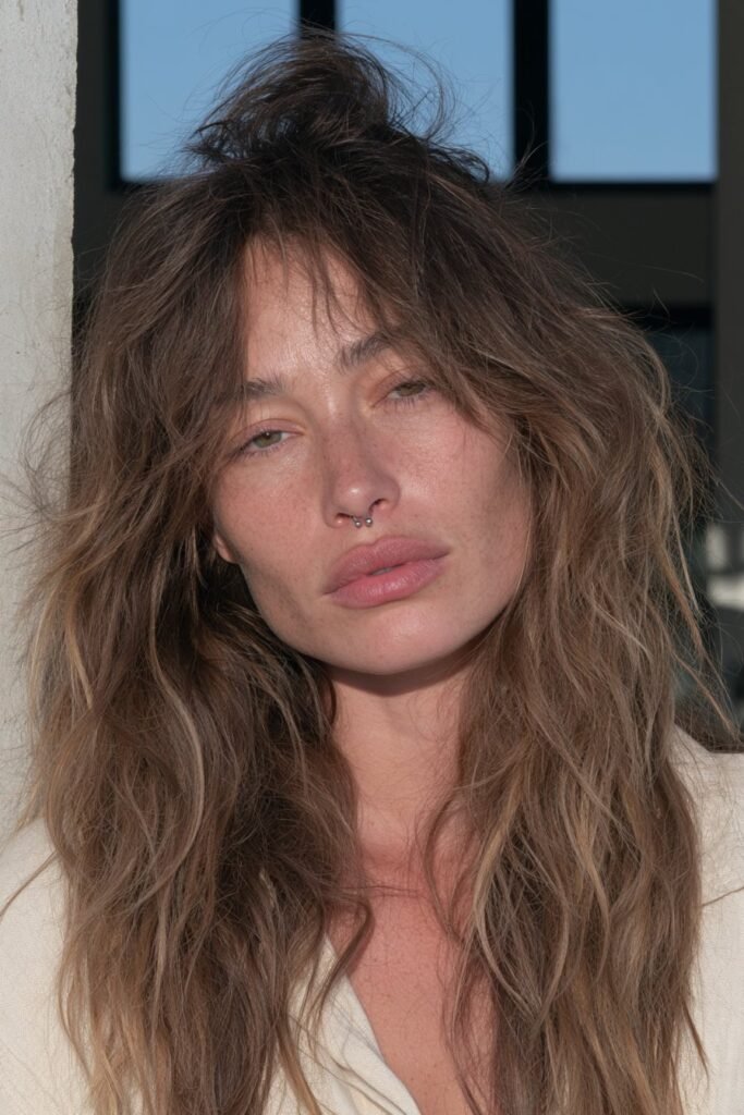 Long brown wolf haircut showing natural textured movement with layered volume and flowing feathered lengths.