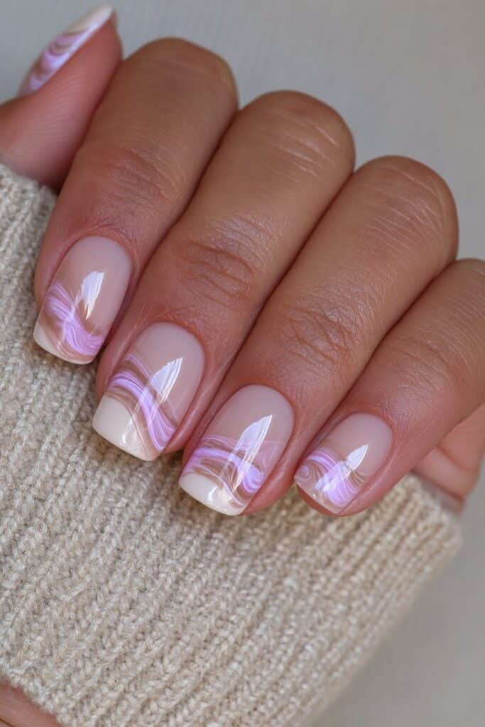 Short cream nails with brown marble swirl patterns.