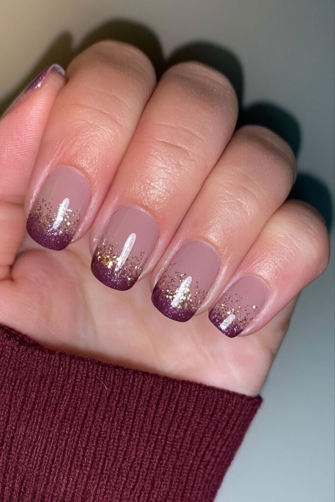Short nude nails with a maroon glitter gradient.