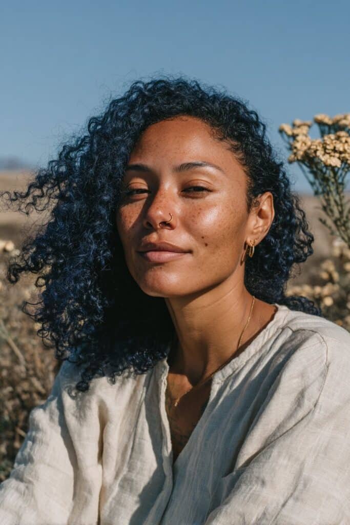 Medium close-up portrait featuring defined curls enhanced with midnight blue color