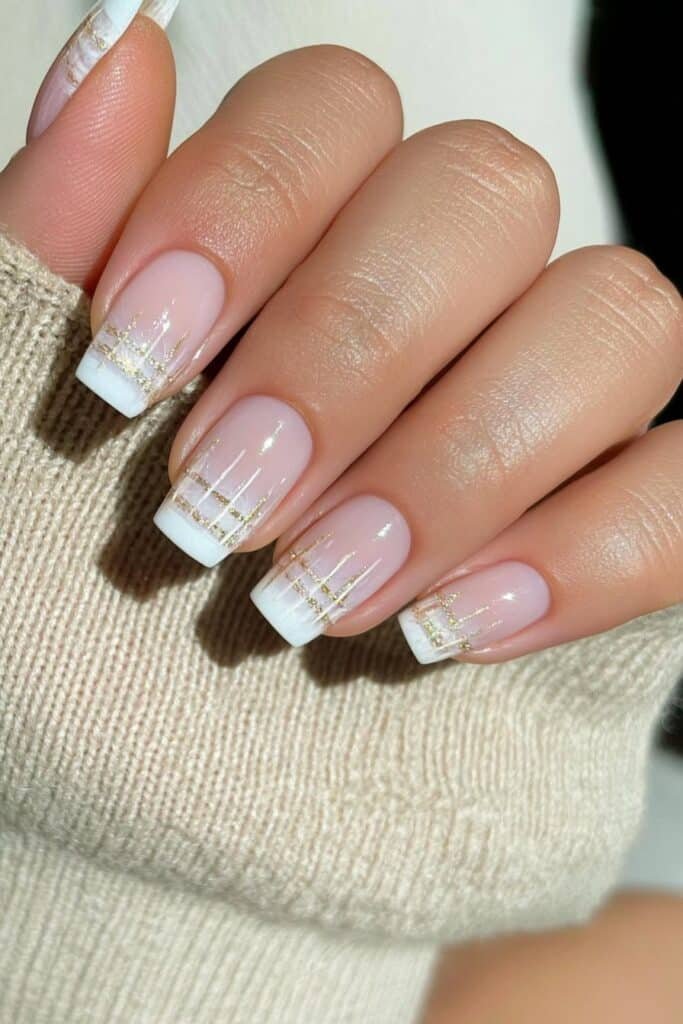 Short milky beige nails with delicate gold accents.