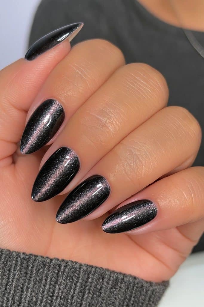 Short black almond nails with dimensional magnetic cat-eye shimmer.