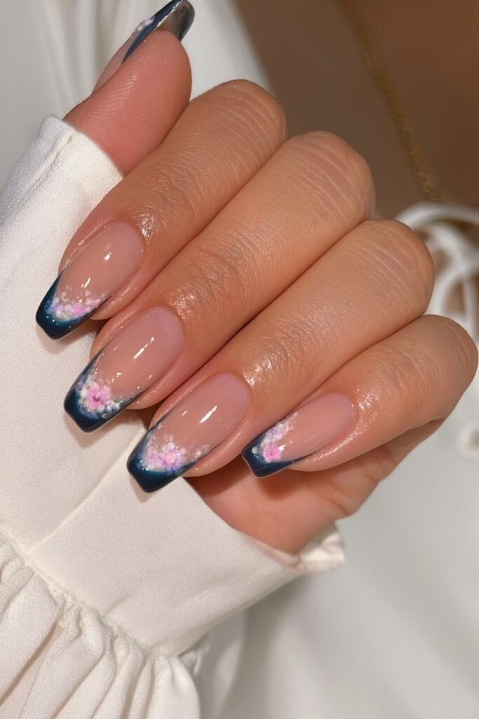 Short nude nails with elegant deep navy French tips with floral detail.