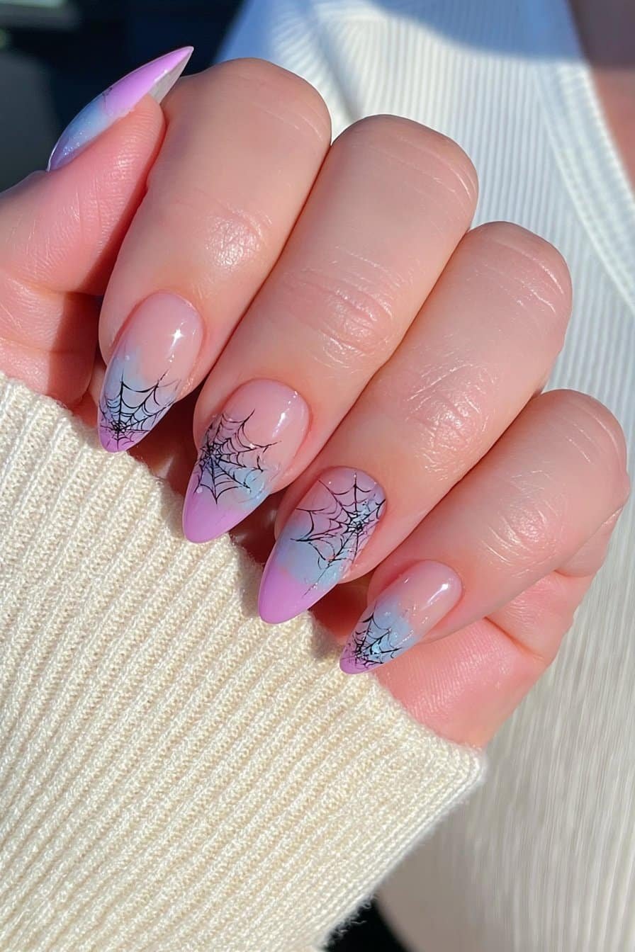 Short almond nails with negative-space sections and delicate black spiderwebs.