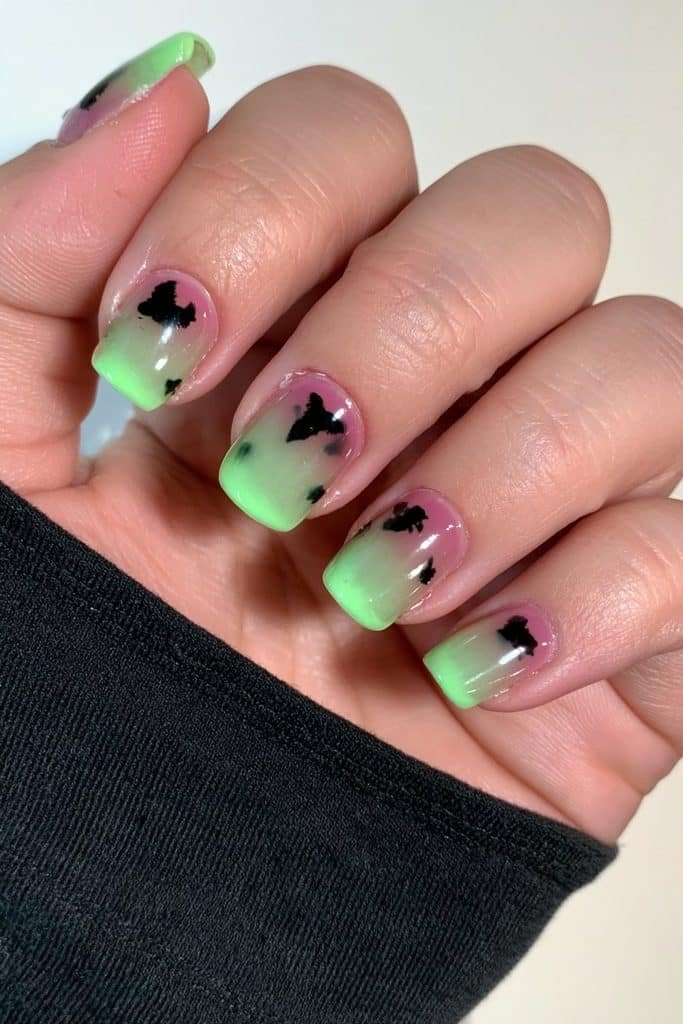 Short translucent neon green jelly nails with tiny black Halloween motifs.