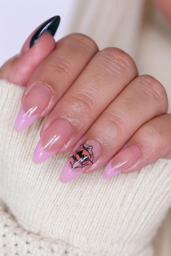 Short nude almond nails with pink details and one tiny spiderweb-pumpkin accent.