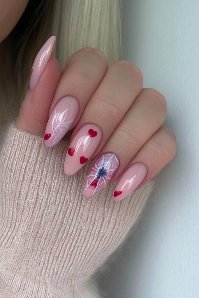 Baby pink nails with spider webs and tiny heart accents.