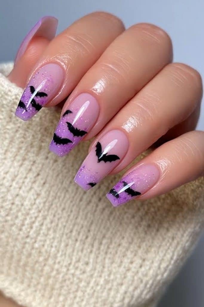 Short lilac nails with a tiny black bat and delicate sparkle accents.