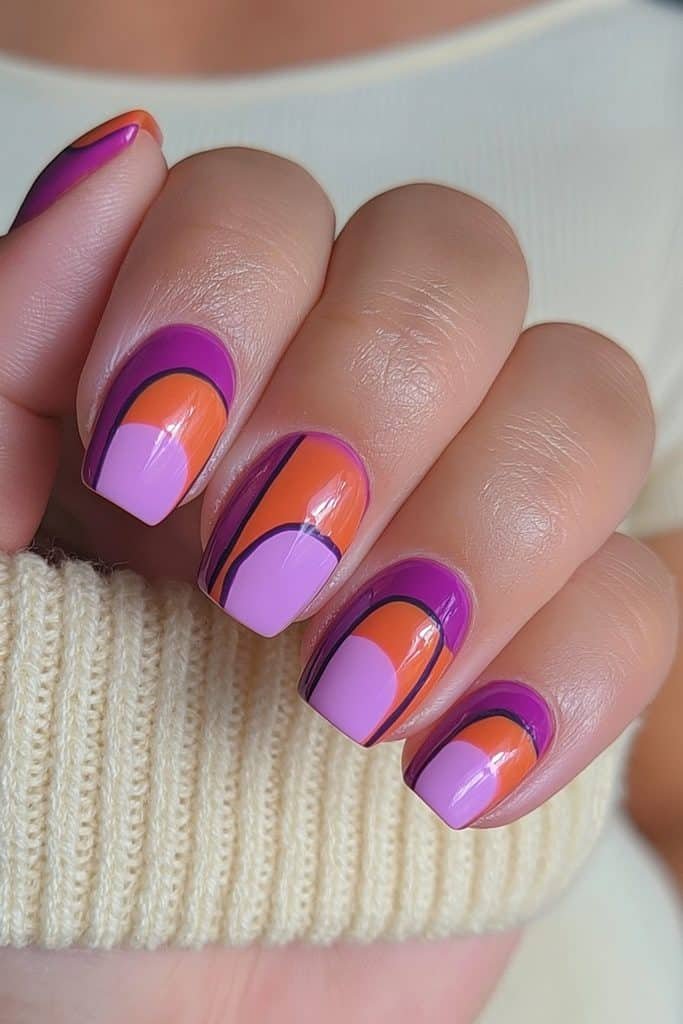 Short nails with bold purple, pumpkin orange, and lavender color blocks.