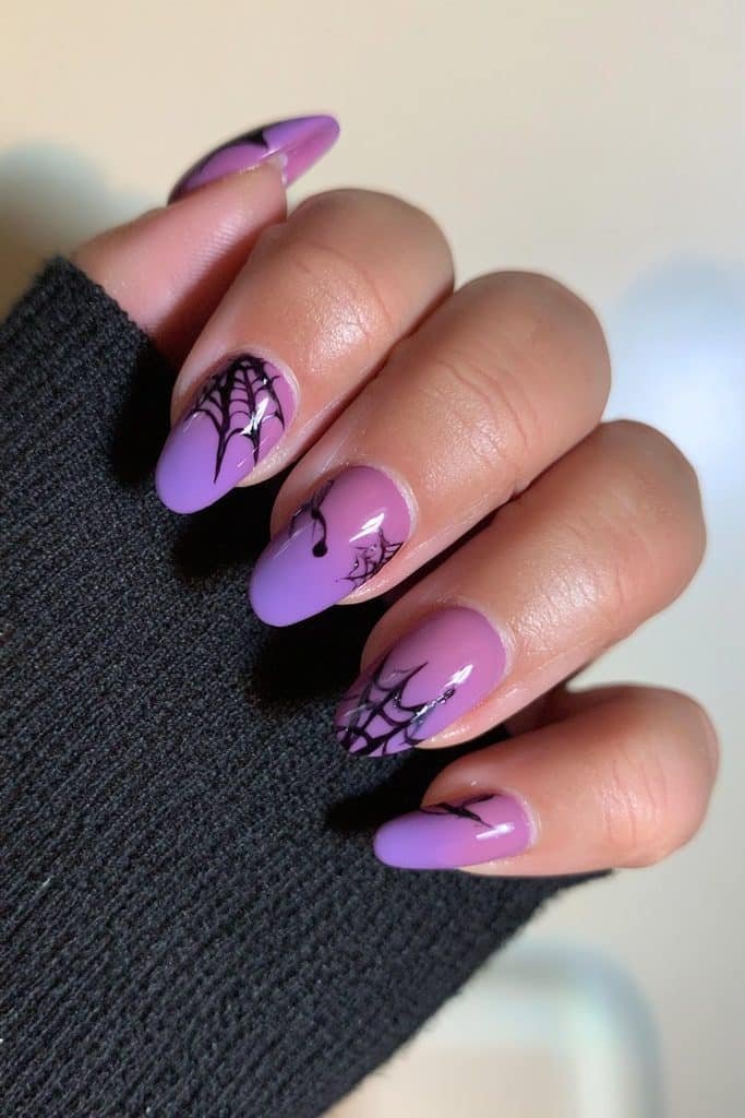 Short matte purple nails with delicate glossy black spiderweb accents.