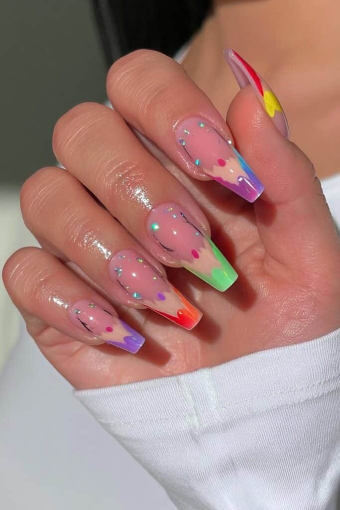 Colorful pencil-inspired nails in yellow, red, blue, green, and purple.