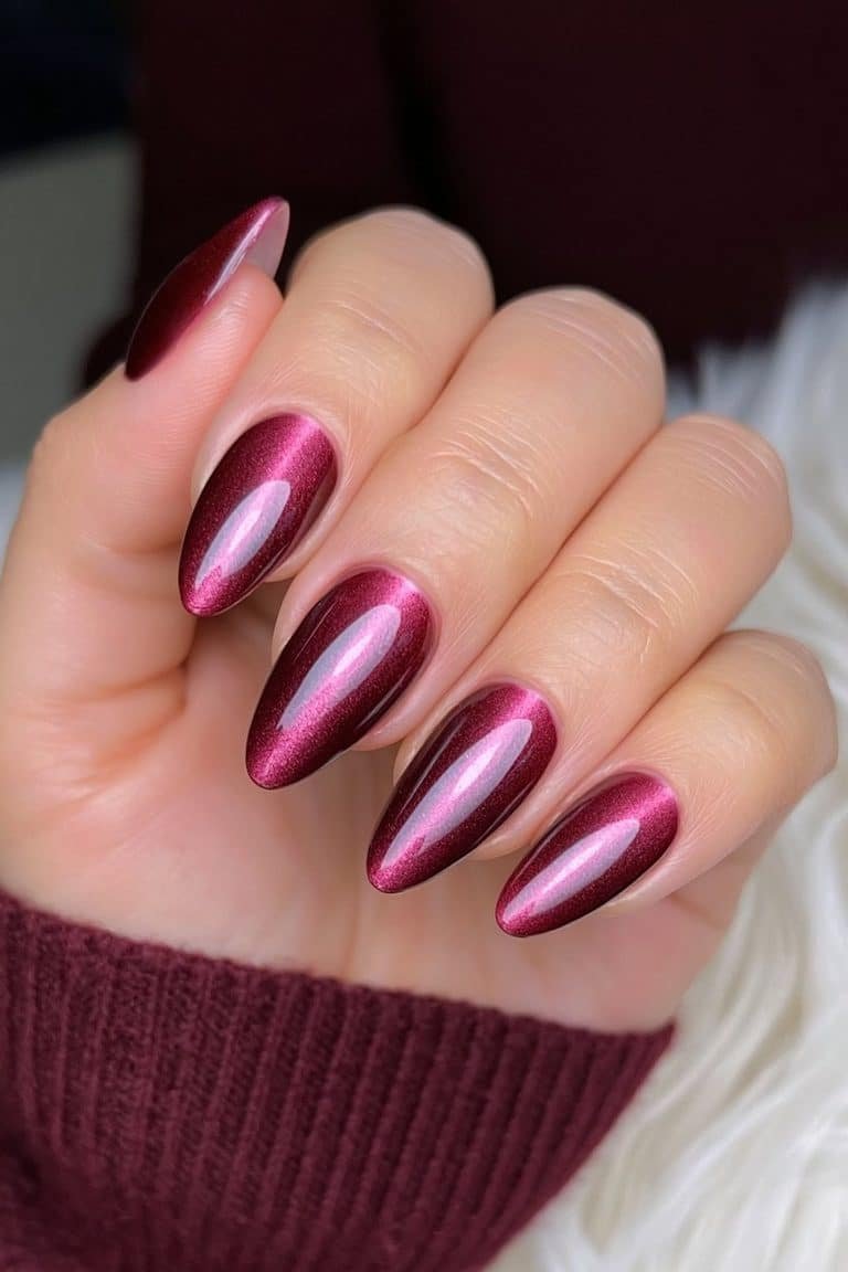 Short ruby-red almond nails with luminous magnetic cat-eye shimmer.