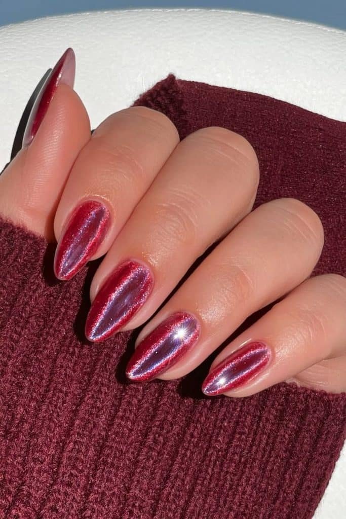 Short ruby-red almond nails with velvet magnetic shimmer and chrome reflection.