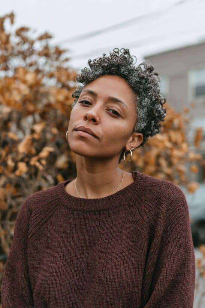 Black woman with a short silver-gray coily TWA and rounded natural texture.