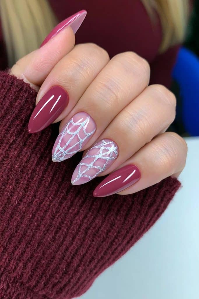 Short wine-red almond nails with delicate silver spiderweb line art.