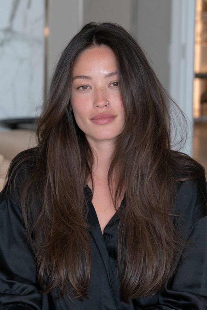 Sleek long brunette wolf cut with smoothly blended layers, polished texture, and feathered ends.
