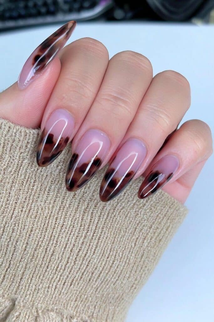 Tortoiseshell almond nails in amber, caramel, chestnut, and espresso tones.
