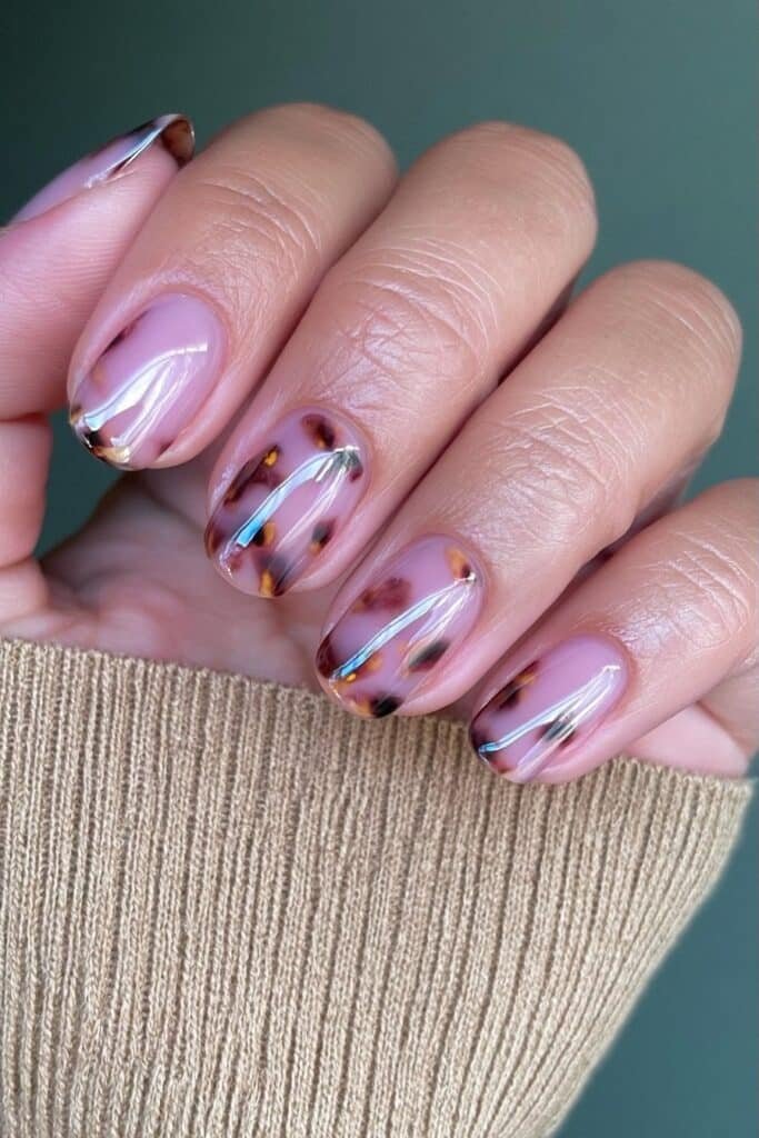Short nude nails with tortoiseshell accent details.