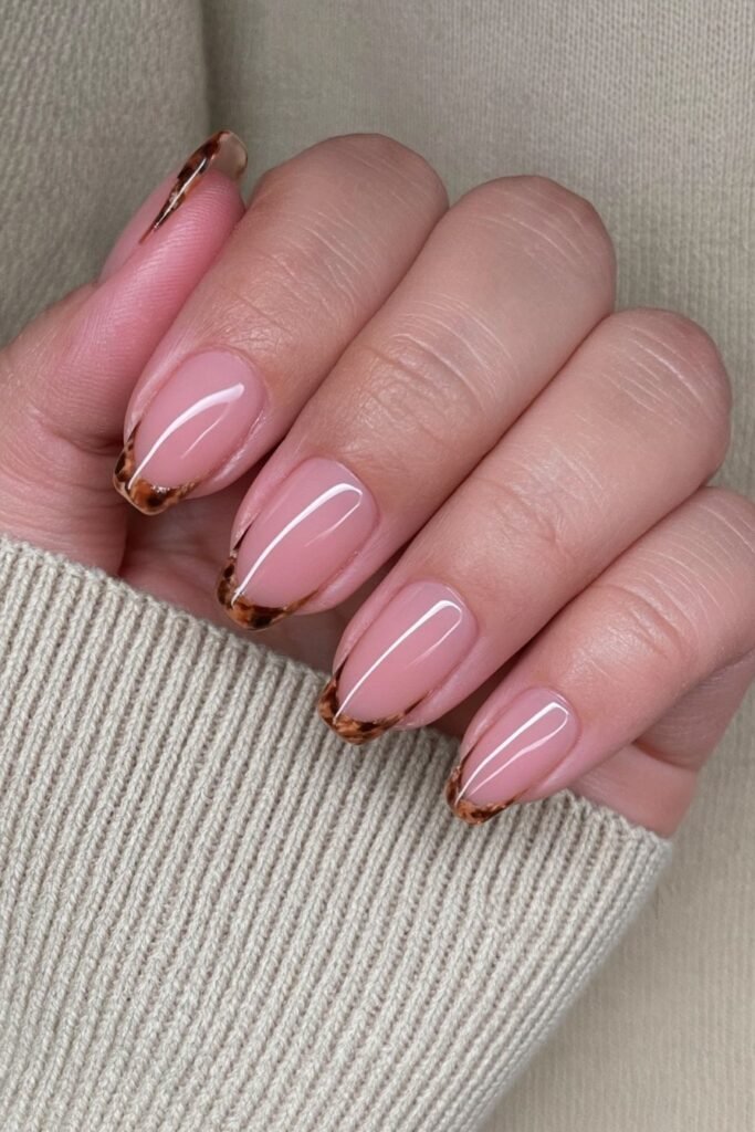 Sheer nude nails with amber and espresso tortoiseshell French tips.