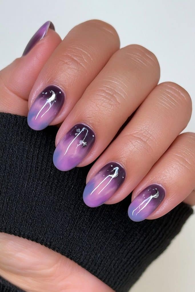 Short rich purple nails with tiny silver crescent moons and stars.