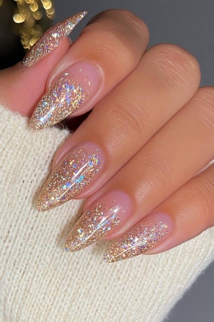 Short almond nails covered in fine gold glitter