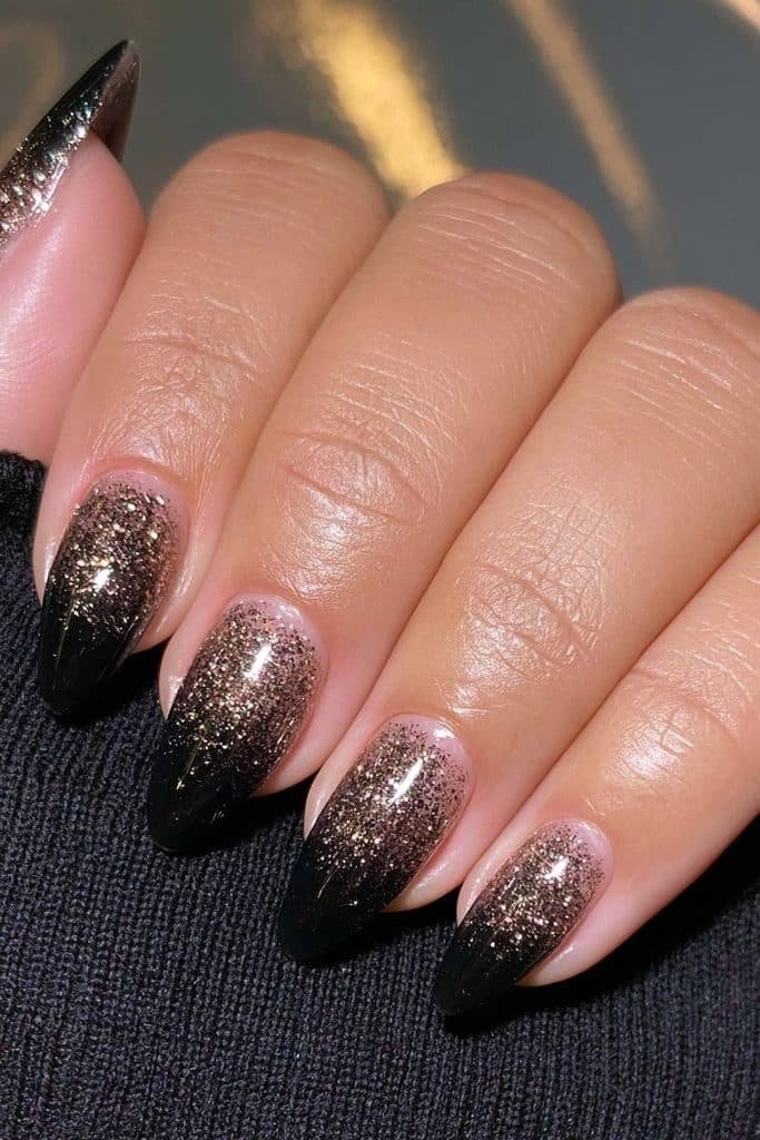 Glossy black nails with sparkling gold glitter accents