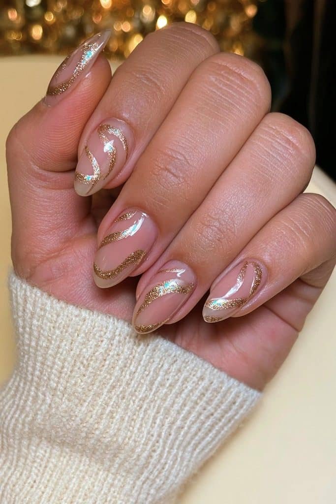 Sheer nude nails with graceful gold glitter swirls