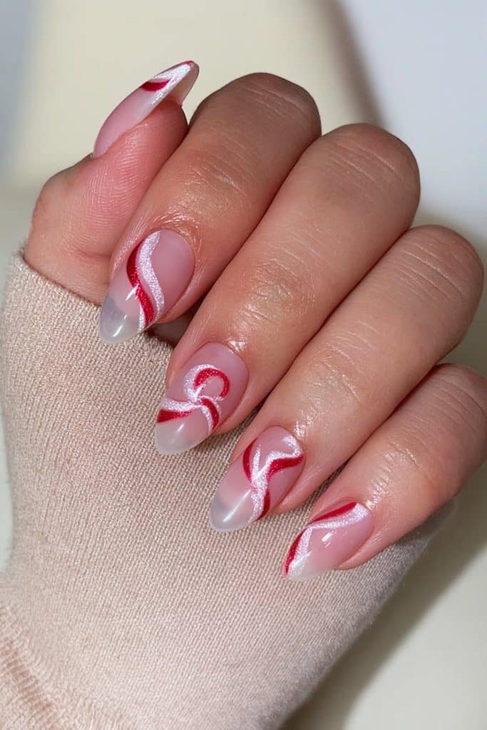 Sheer nude nails with red and white peppermint swirls