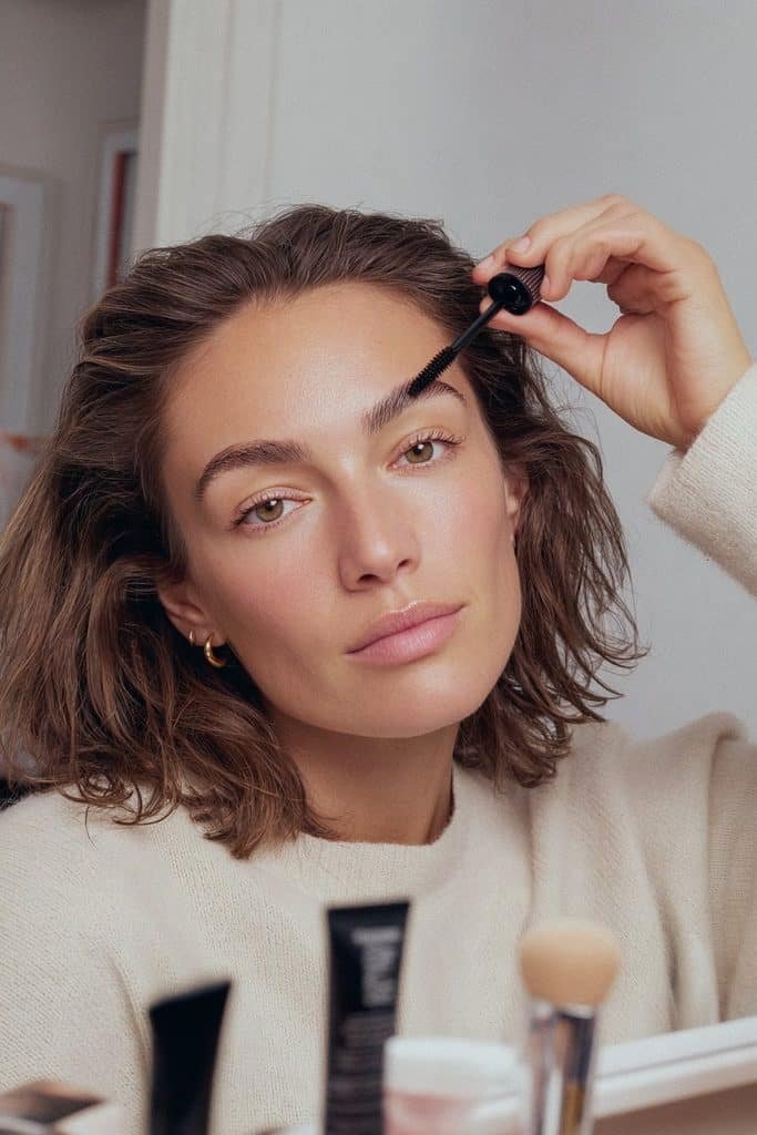 Young woman setting fluffy brows with clear brow gel