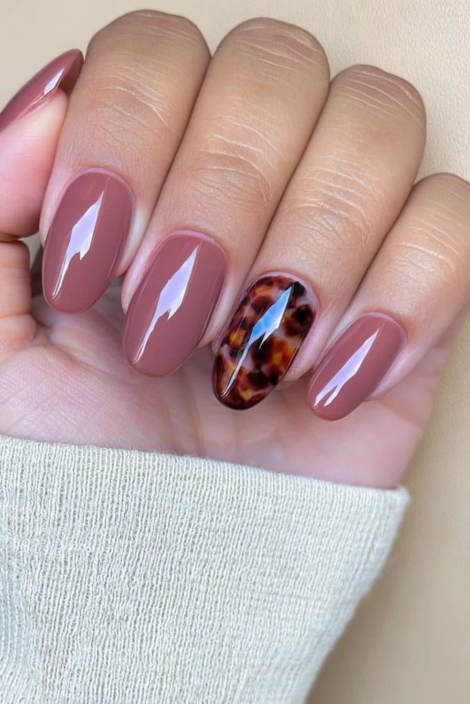 Glossy neutral nails with a detailed tortoiseshell accent