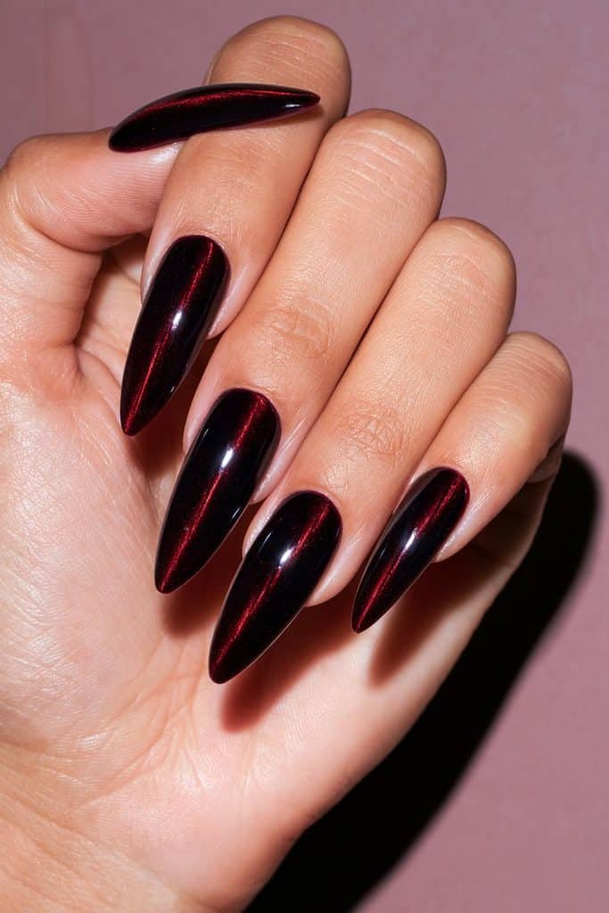 Maroon almond cat eye nails with elongated ruby-red magnetic streaks and a glossy wine-colored finish.
