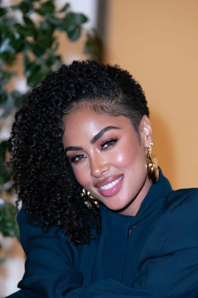 Black woman with an asymmetrical tapered haircut featuring a longer, side-swept top and closely tapered sides.