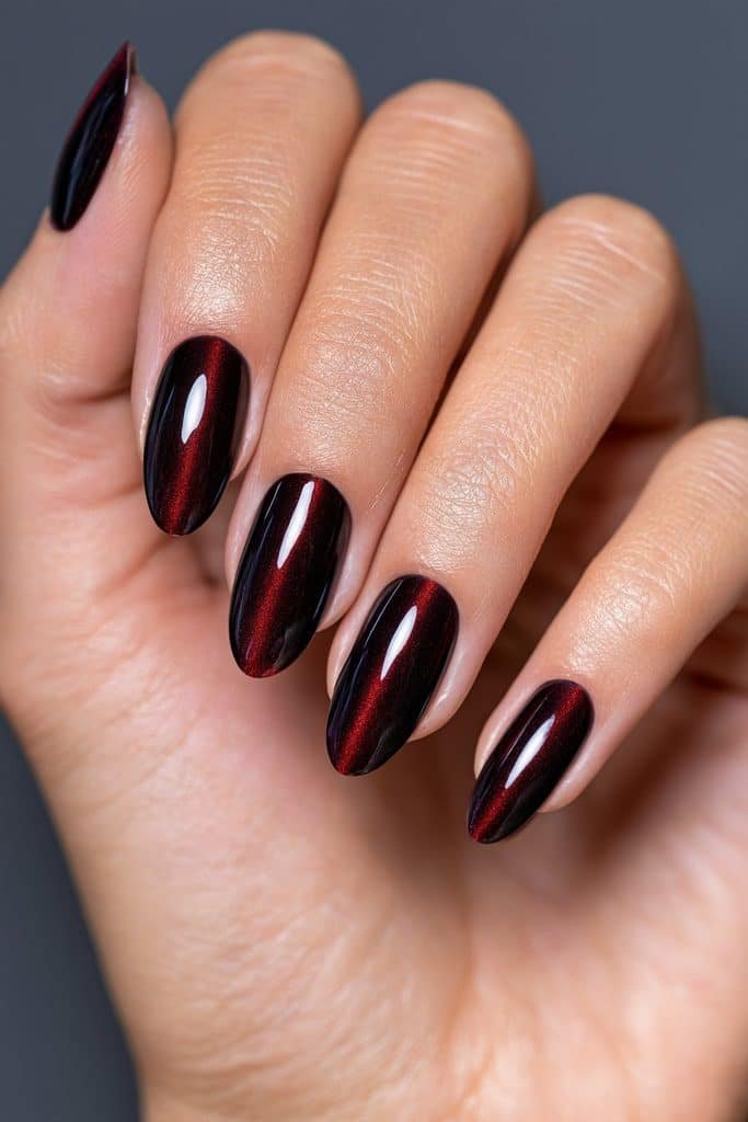 Black cherry maroon cat eye nails with deep burgundy edges, luminous crimson streaks, and a glossy midnight finish.